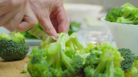 Prepare broccoli in the kitchen by chopping it into smaller pieces Video stock 119259185
