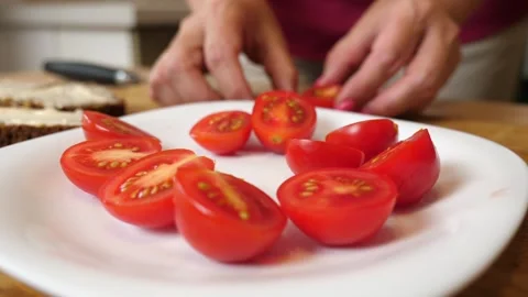 To prepare the dish, cherry tomatoes are cut in half with a knife. Stock Footage 282573358