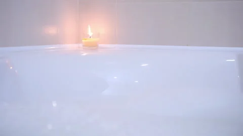 Prepared bath with foam burning candle for relaxation at home, close-up view. Video stock 272905504