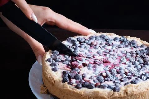 Prepared berry pie on the table in the kitchen the cook cuts a piece of a Stock Photos
