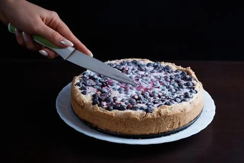 Prepared berry pie on the table in the kitchen the cook cuts a piece of a Stock Photos