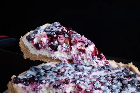 Prepared berry pie on the table in the kitchen the cook cuts a piece of a Stock Photos
