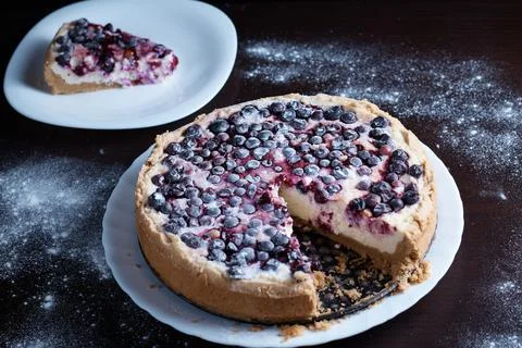 Prepared berry pie on the table in the kitchen the cook cuts a piece of a Stock Photos