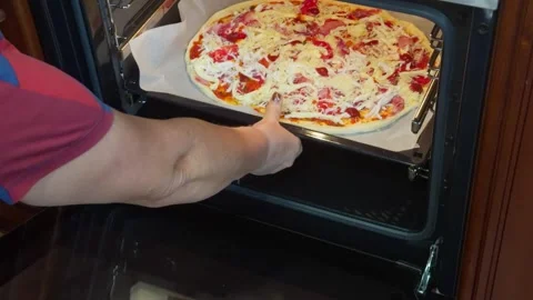 A prepared pizza on a baking tray lined with parchment paper is placed in t.. Stock Footage 347389370