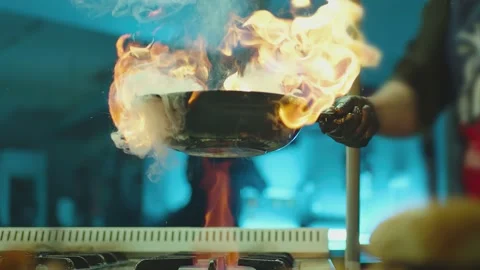 Prepares dish meat in a pan with open flames .  Slow Motion Stock Footage 157774221