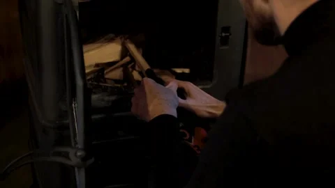 Prepares to ignite firewood in a stove showcasing the lighting process Video stock 319962989
