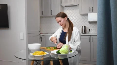 Prepares salad, cuts vegetables, slices cucumbers Stockbeeldmateriaal 308235887