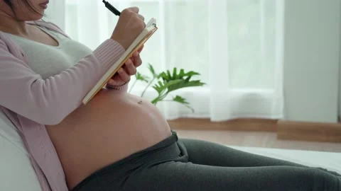 Preparing and check list for mother. A pregnant woman write down on book abou Vídeos de archivo 217967333