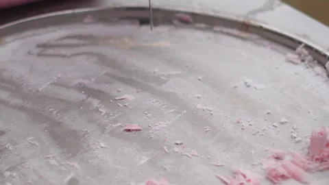 Preparing and scraping fresh rolled ice cream on a freezing metal pan at a st Stock Footage 344851410
