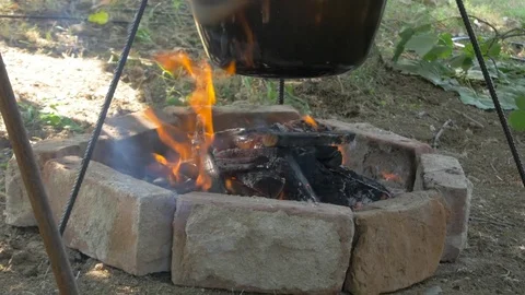 Preparing beef stew or goulash in cauldron on campfire, tilt up, outdoors. Stock Footage 81558251
