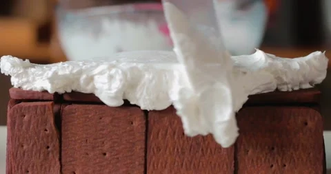 Preparing biscuit cake, lined cocoa biscuits are covered with pastry cream Stock Footage 248139458