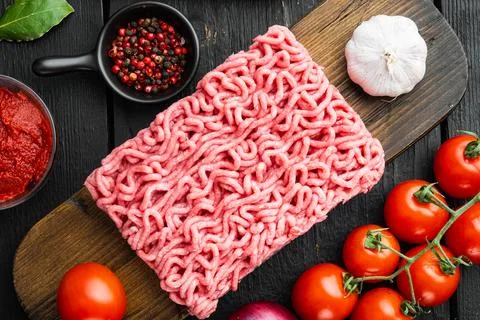 Preparing Bolognese sauce ingredients, minced meat, tomatoe, herbs, on wooden Foto stock