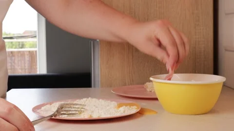 Preparing breaded pork chops by dipping each slice in beaten egg from a yel.. Stock Footage 320955009