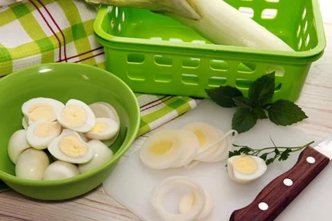 Preparing breakfast. Cutting leek and boiled quail eggs. Stock Photos