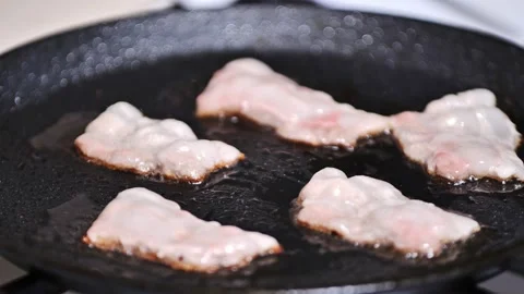 Preparing breakfast. frying bacon close-up slow mo Stock Footage 167898283