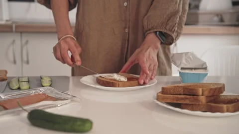 Preparing breakfast with toast, butter, and cucumber in a kitchen setting Stock Footage 340193534