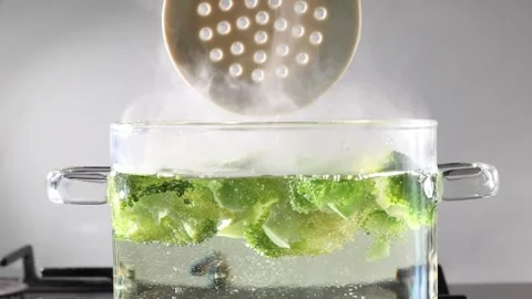Preparing broccoli for blanching: stirring florets with a slotted spoon on the Stock Footage 345426406