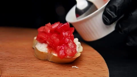 Preparing bruschetta with diced tomatoes on toasted bread slice in kitchen Stock Footage 335191723