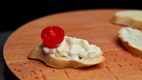 Preparing bruschetta with sliced tomatoes on toasted bread in kitchen setting Stock Footage 335191694