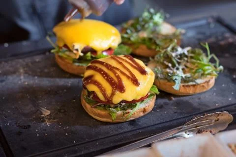 Preparing burger adding the sauce on the cream cheese. Three burgers. Stock Photos