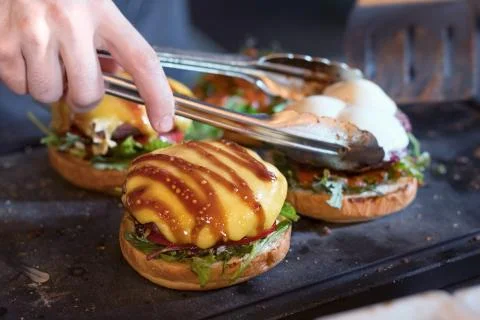 Preparing burger adding the sauce on the cream cheese. Three burgers. Stock Photos