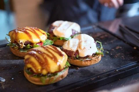 Preparing burger adding the sauce on the cream cheese. Three burgers. Stock Photos