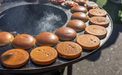 Preparing burger buns. The buns are arranged in a circle on a hot flat-top gr Stock Photos