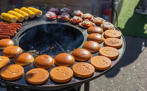Preparing burger buns. The buns are arranged in a circle on a hot flat-top gr Stock Photos