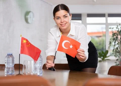 Preparing for business negotiations - woman sets small flags of countries of Stock Photos