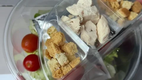 Preparing Caesar salad in a plastic container with all the ingredients on the Stock Footage 323375377