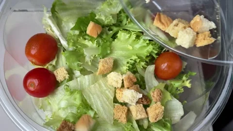 Preparing Caesar salad in a plastic container with all the ingredients on the Stock Footage 323472209