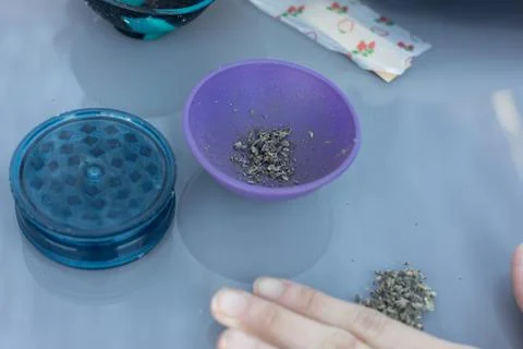 Preparing cannabis creating a joint with grinder and bowl Fotos de archivo