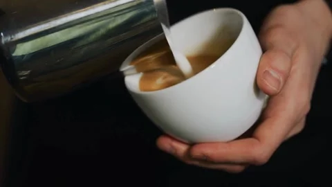 Preparing Cappuccino Coffee. Milk being poured into a mug with coffee. Stock-Footage 334648238