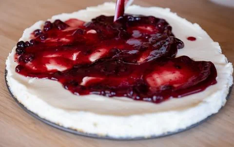 Preparing cheesecake with red syrup of red berries and strawberries with ch.. Stock Photos