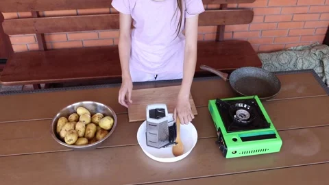 Preparing to cook potatoes using a grater and portable stove outdoors Stock Footage 297358366