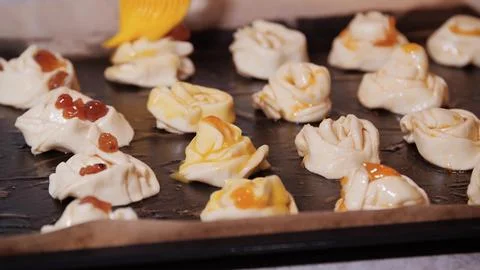 Preparing cruffins with egg wash and toppings for baking on a baking sheet Stock Photos