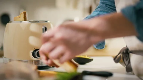 Preparing a delicious breakfast with toast and avocado on a sunny kitchen mo Stock Footage 304271213