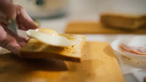 Preparing a delicious breakfast with toasted bread and a fried egg on a wood Stock Footage 323875205