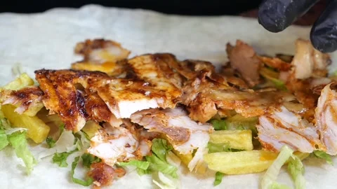Preparing delicious chicken shawarma wrap with fries and lettuce, close up .. Stock Footage 333158626