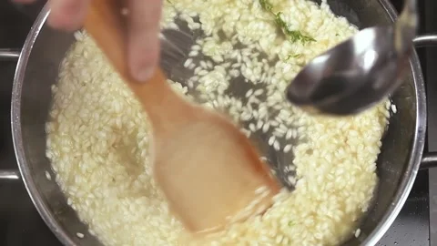 Preparing of delicious risotto in the frying pan. Pouring of broth. Stock Footage 154370561