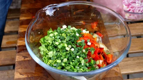 Preparing a delicious side dish of vegetables and herbs for a pork barbecue Video stock 128921332