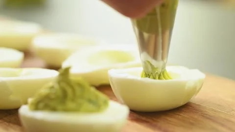 Preparing deviled eggs with avocado and basil. Stock Footage 165616389