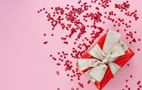 Preparing for different holidays. Red gift box with gold bow and red sequins on Stock Photos