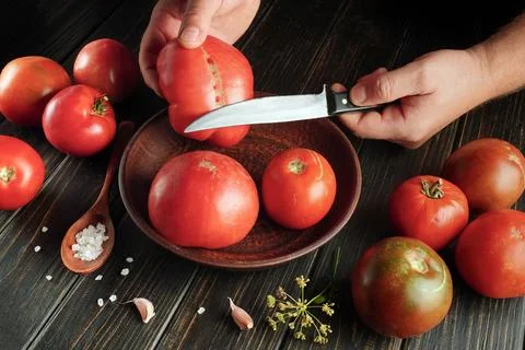 Preparing dishes or preserving fresh tomato at home. Hands with a knife for.. Stock Photos