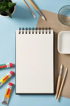 Preparing to draw. Empty notebook, tubes of acrylic paint, brushes, a glass.. Stock Photos