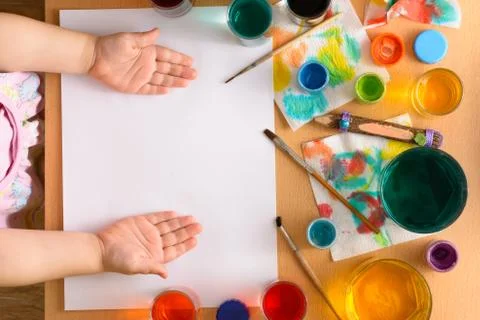Preparing to drawing. Blank sheet among watercolors and brushes. Child's hand Stock Photos