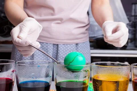 Preparing for Easter - coloring eggs in home kitchen female hands in rubber g Stock Photos