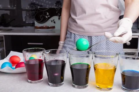 Preparing for Easter - coloring eggs in home kitchen female hands in rubber g Stock Photos