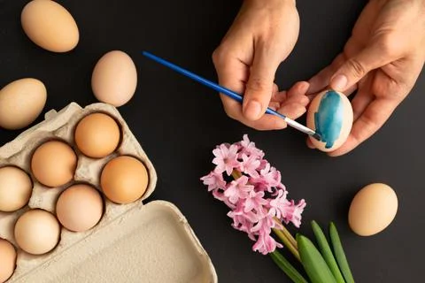 Preparing for Easter. Father painting Easter eggs on black background. Easter Stock Photos