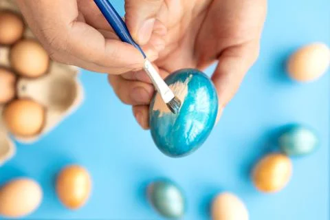 Preparing for Easter. Father painting Easter eggs on blue background. Easter day Stock Photos
